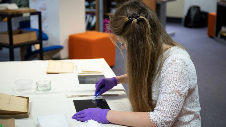 Colour image of Beken volunteer cleaning glass plate negative