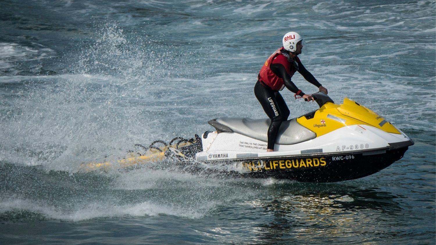 An RNLI lifeguard on a rescue watercraft in the sea.