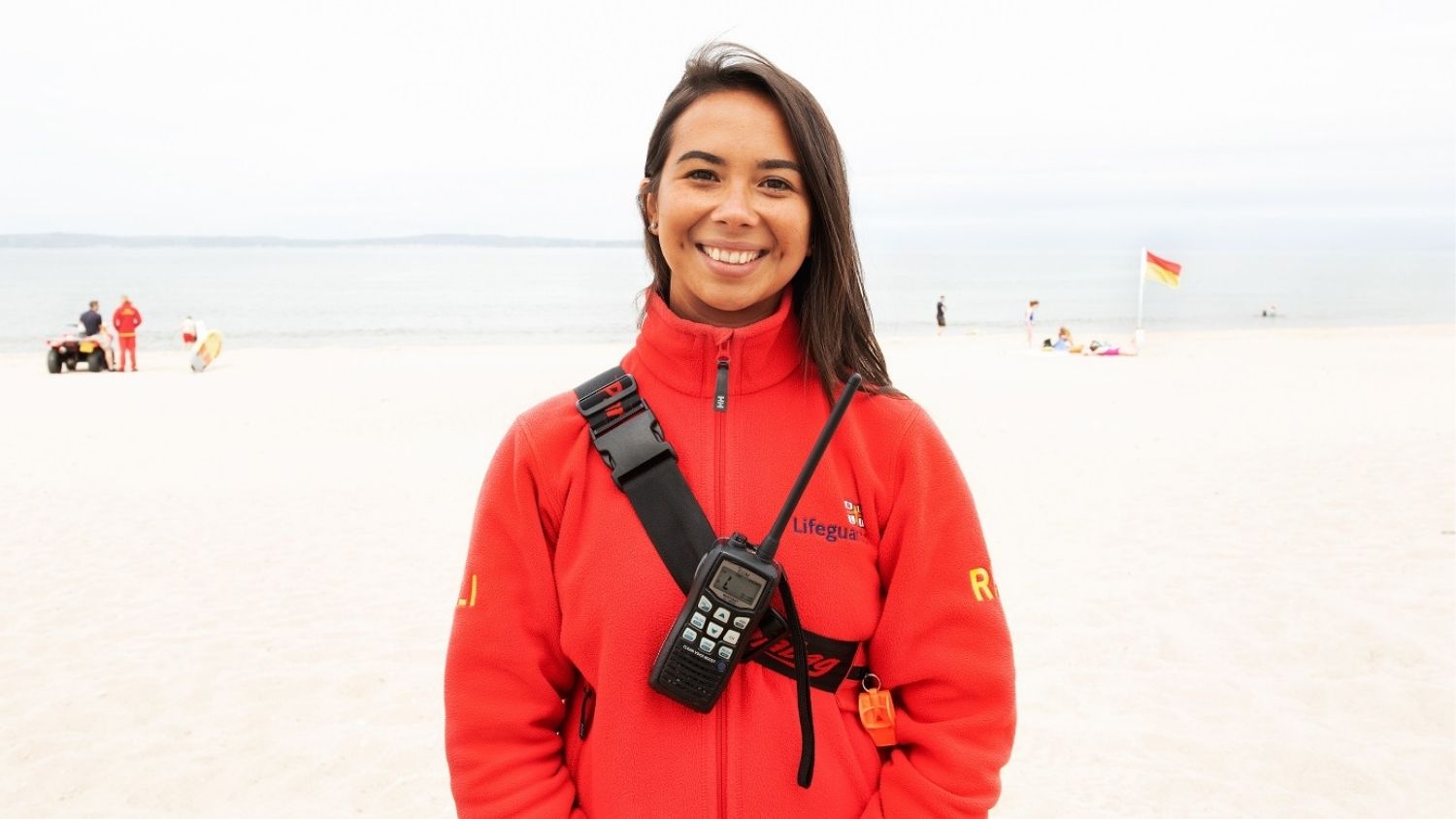 An RNLI lifeguard wearing her lifeguard kit on the beach.