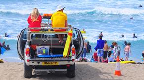 RNLI lifeguards at Holywell Bay, Newquay, monitoring people in the sea from a patrol vehicle