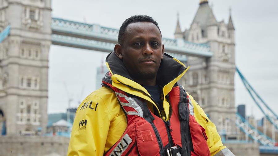 Tower RNLI Crew Member Nazrawi Mamoneh stands in front of Tower Bridge in London