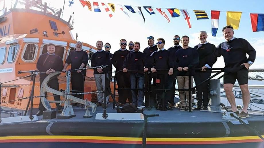 The crew at Yarmouth RNLI stand on the deck of their lifeboat, with brightly coloured nautical bunting flying in the wind above them