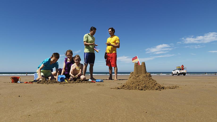 A lifeguard talking to a family on the beach