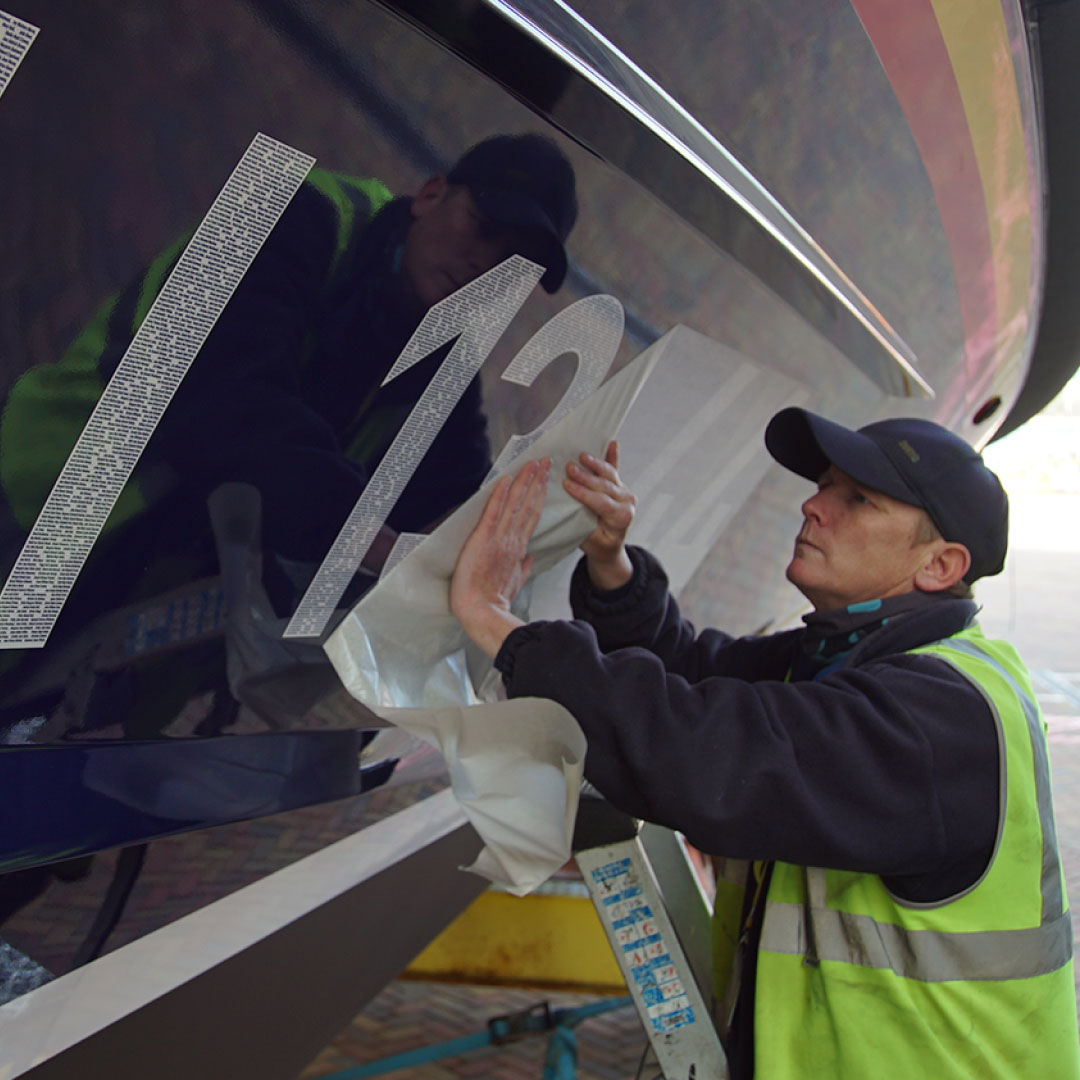 A man putting on a decal onto a shannon class lifeboat