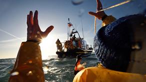 St Ives RNLI lifeboat crew throwing rope to fisherman in the water