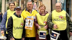 Five fundraising volunteers on a city street with collection buckets facing the camera
