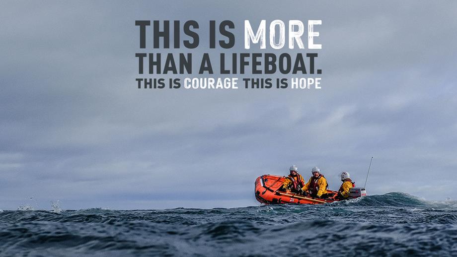 Three lifeboat volunteers are aboard an inshore lifeboat, powering out to sea. The waves are choppy and the sky is grey.