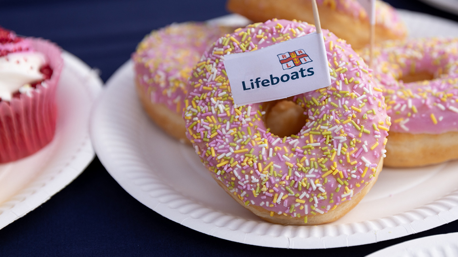 Donuts on a paper plate with an RNLI lifeboats flag