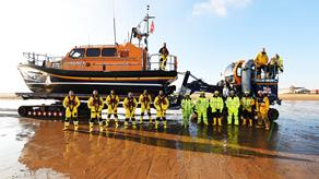 Group shot of RNLI lifeboat volunteers stood with their Shannon class lifeboat on the launch vehicle