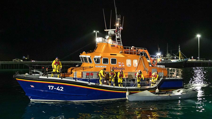 A small grey rowing boat alongside Thurso’s Severn class lifeboat, where six crew members are standing on deck