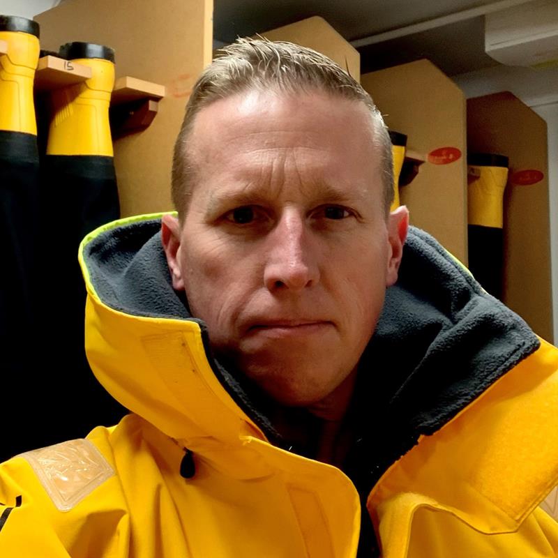Andy Martin is in a portacabin wearing crew kit and looking at the camera.