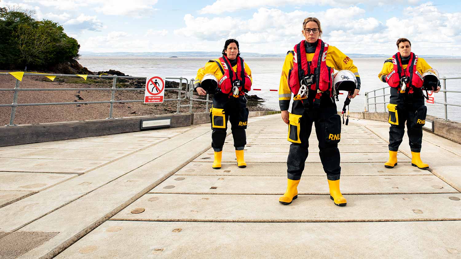 3 lifeboat crew female members in kit standing in triangle formation