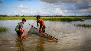 Faisal (11) and Jamal (18) fish on the floodwaters after a monsoon. Cox s Bazar. Bangladesh. One inch of water international project.