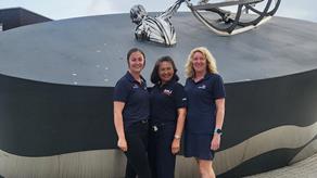 Three members of the water safety team in front of the RNLI memorial sculpture in Poole.