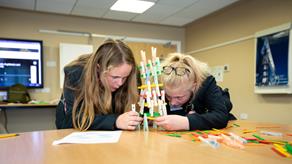 Two school girls building a peg structure in a classroom
