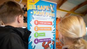 Two children looking at an RNLI banner about being safe and having fun.