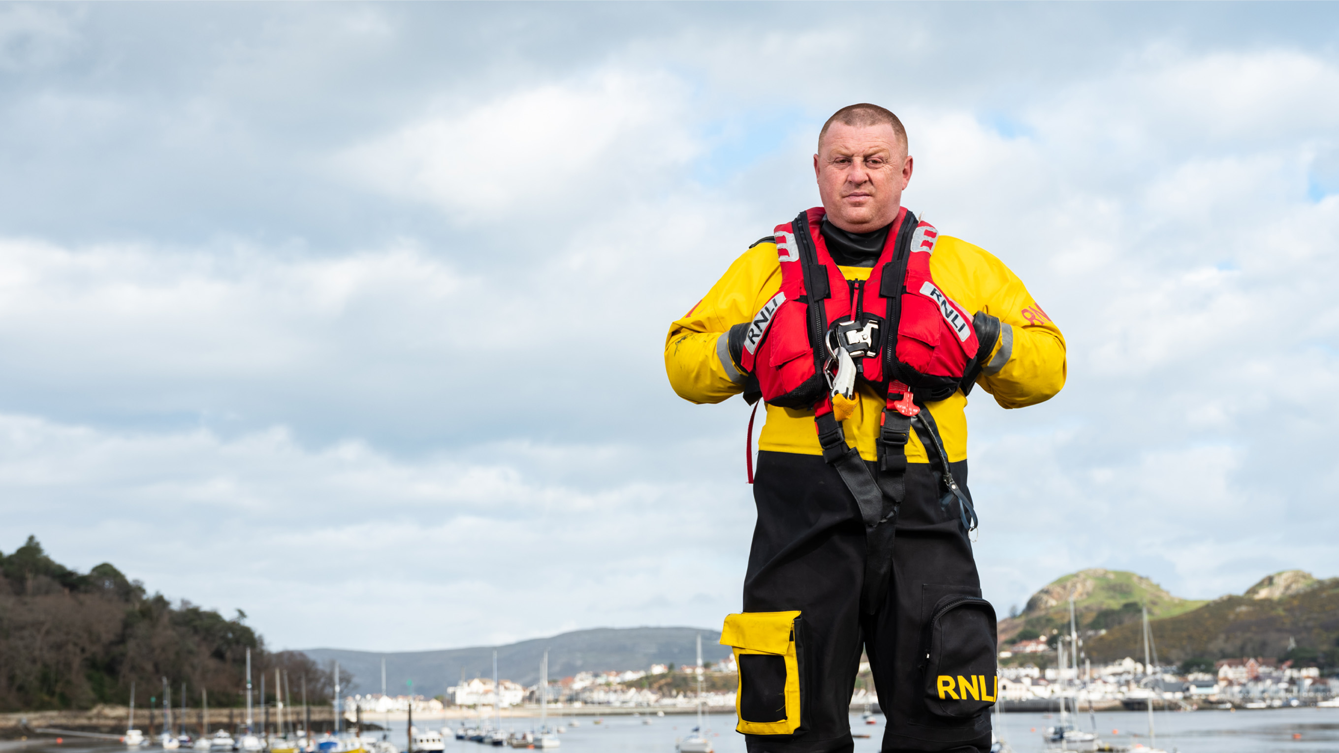 Lifeboat Crew Member Steve Tustin is standing in front of a blue roller door.